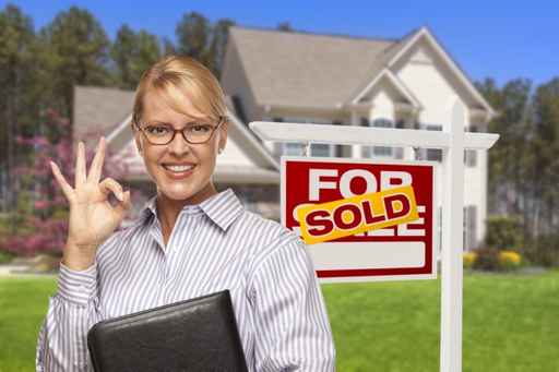 Real Estate Agent in Front of Sold Sign and House