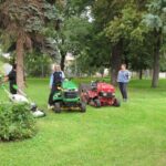 people standing near lawn mower tractor in a lawn