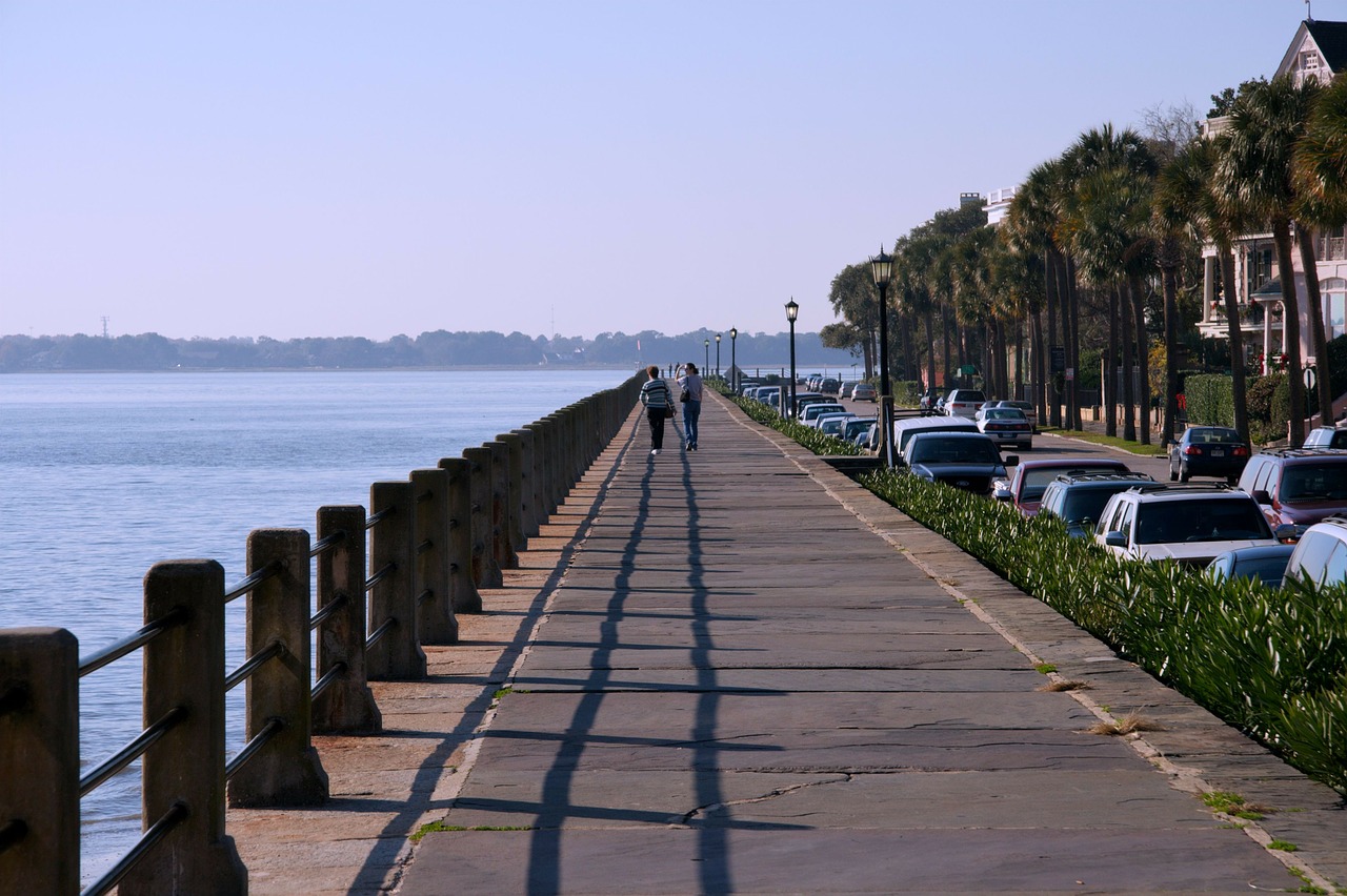 People walking on a sidewalk by the ocean