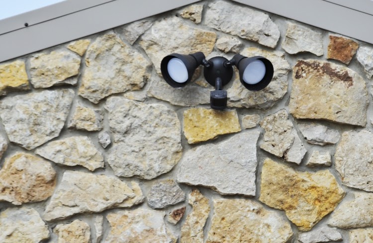 two-headed, black floodlight mounted on stone wall