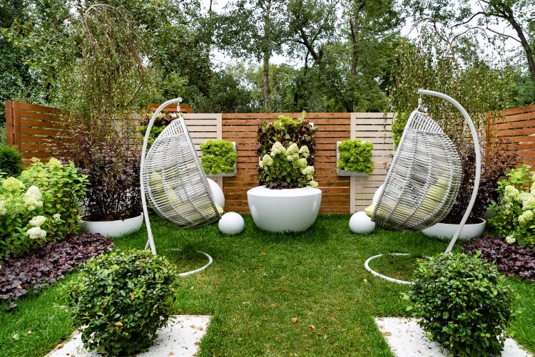 Wooden vertical garden wall in backyard garden with wicker basket seating and variety of plants