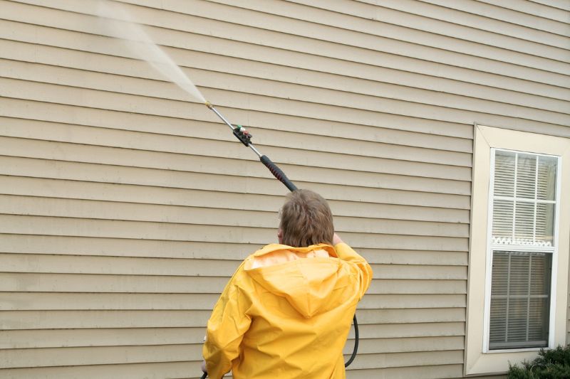 a man pressure washing the siding of a house
