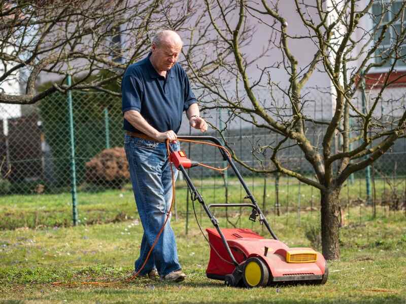 senior man verticutting his lawn