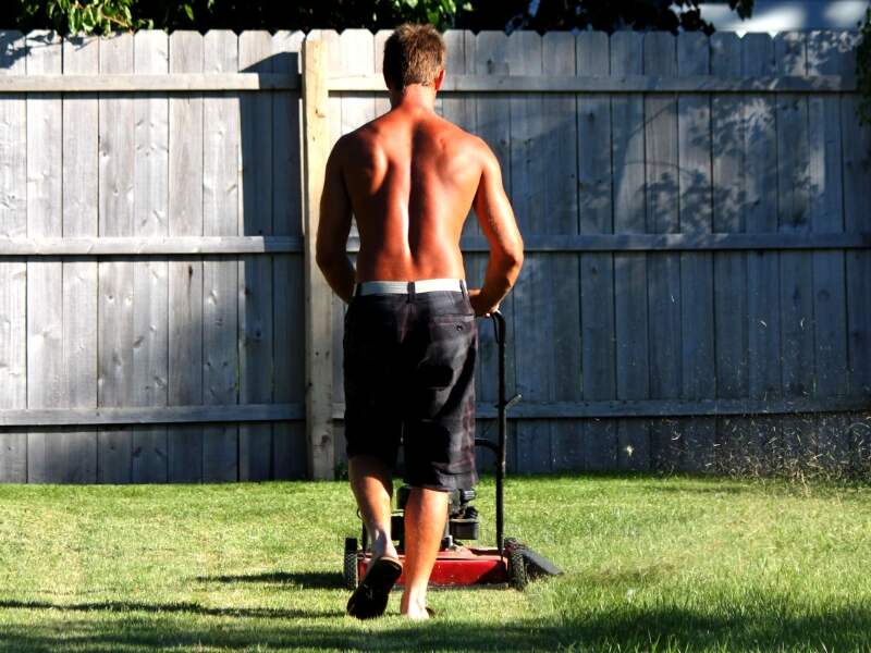 man mowing the lawn in the heat with his shirt removed