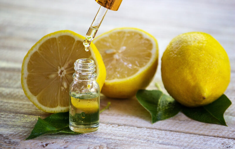 A bottle of lemon essential oil with lemons