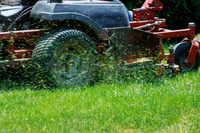 Lawn mower cutting overgrown grass