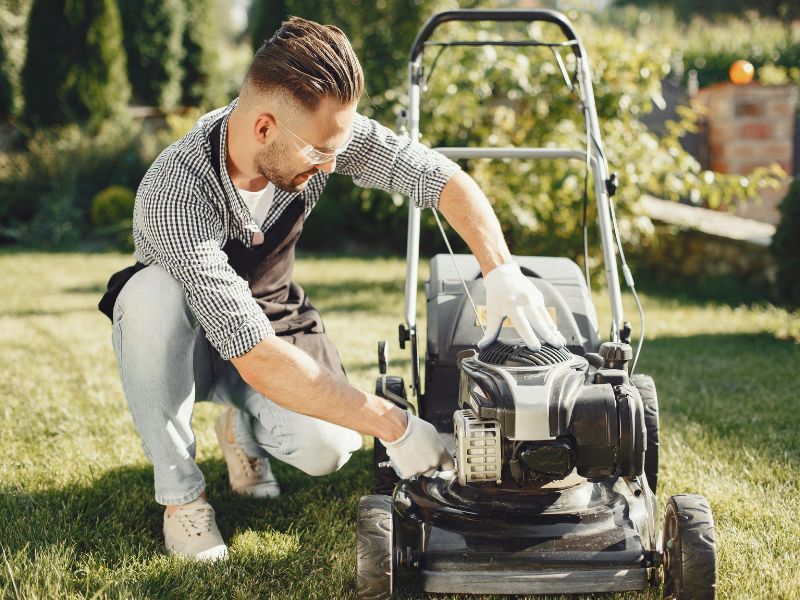 Man repairing lawn mower, maintenance