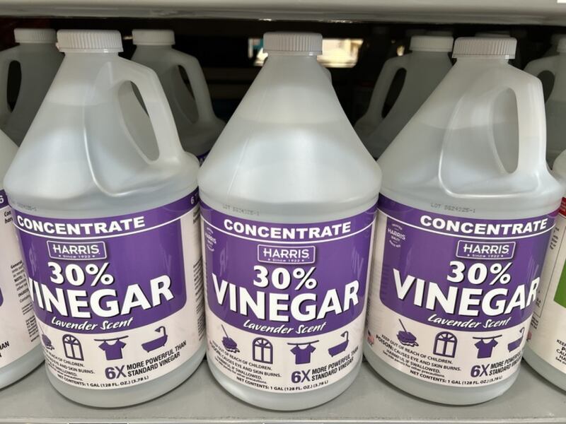 Three gallon-sized bottles of Harris 30% Vinegar Concentrate with lavender scent displayed on a store shelf. The bottles feature purple and white labels highlighting that the product is 6 times more powerful than standard vinegar and intended for cleaning, laundry, and general household use.